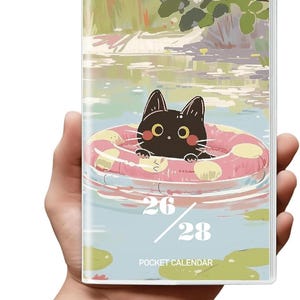 May include: Pocket calendar featuring a black cat in a pink and white inner tube floating in water. The calendar has a serene illustration of a pond with flowers and the dates 26/28. The words "POCKET CALENDAR" are printed at the bottom.