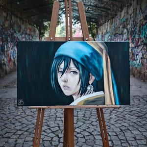 May include: An oil painting on canvas of a woman with blue headwear and a pearl earring, reminiscent of Vermeer's "Girl with a Pearl Earring." The artwork is displayed on a wooden easel, set against a dark background.