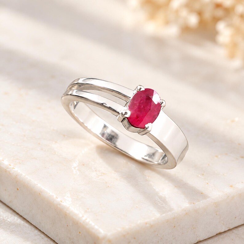 Natural oval ruby ring worn on a woman’s finger to show realistic scale, proportion and elegant everyday styling. The 0.69 ct pinkish red ruby creates a refined focal point against the polished silver-tone ring design. This lifestyle view helps buyers visualize the ruby gemstone ring as July birthstone jewelry, an anniversary ring, birthday gift for her, romantic jewelry gift, promise ring or sophisticated natural gemstone accessory for everyday and special occasion wear.