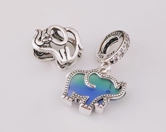 May include: Two silver elephant charms. One is a solid openwork design. The other is a pendant with a blue and green enamel elephant design, accented with small silver beads. The pendant has a silver ring with clear stones.