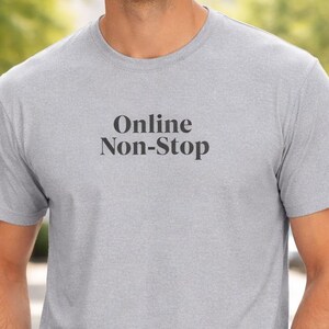 Peut inclure: Un t-shirt gris clair avec le texte "Online Non-Stop" en noir. Le t-shirt est porté avec un jean bleu. Le t-shirt est fait d'une matière douce.