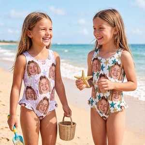 May include: Two young girls wearing matching swimsuits with a repeating face pattern, standing on a sandy beach. One swimsuit is white with blue and yellow stars, the other is light purple with seashells. One girl holds a starfish and the other holds a small basket.