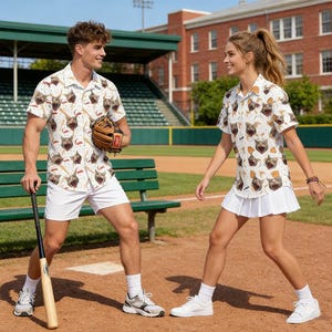Könnte beinhalten: Zwei Personen tragen passende weiße Hemden mit einem sich wiederholenden Muster aus Möpsen und Baseballschlägern. Eine Person hält einen Baseballschläger und einen Handschuh, die andere einen weißen Faltenrock. Baseballfeld im Hintergrund.
