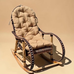 May include: A wooden rocking chair with a tan cushion and backrest. The chair has curved armrests with a dark brown trim and a woven seat. The chair is designed for comfort and relaxation.