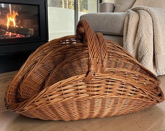 Può includere: Un grande cesto in vimini marrone curvo caratterizzato da un design intrecciato con una robusta maniglia centrale. Il cesto ha una distinta forma semicircolare con una base ampia e aperta e giunchi di salice intrecciati in tutta la struttura.