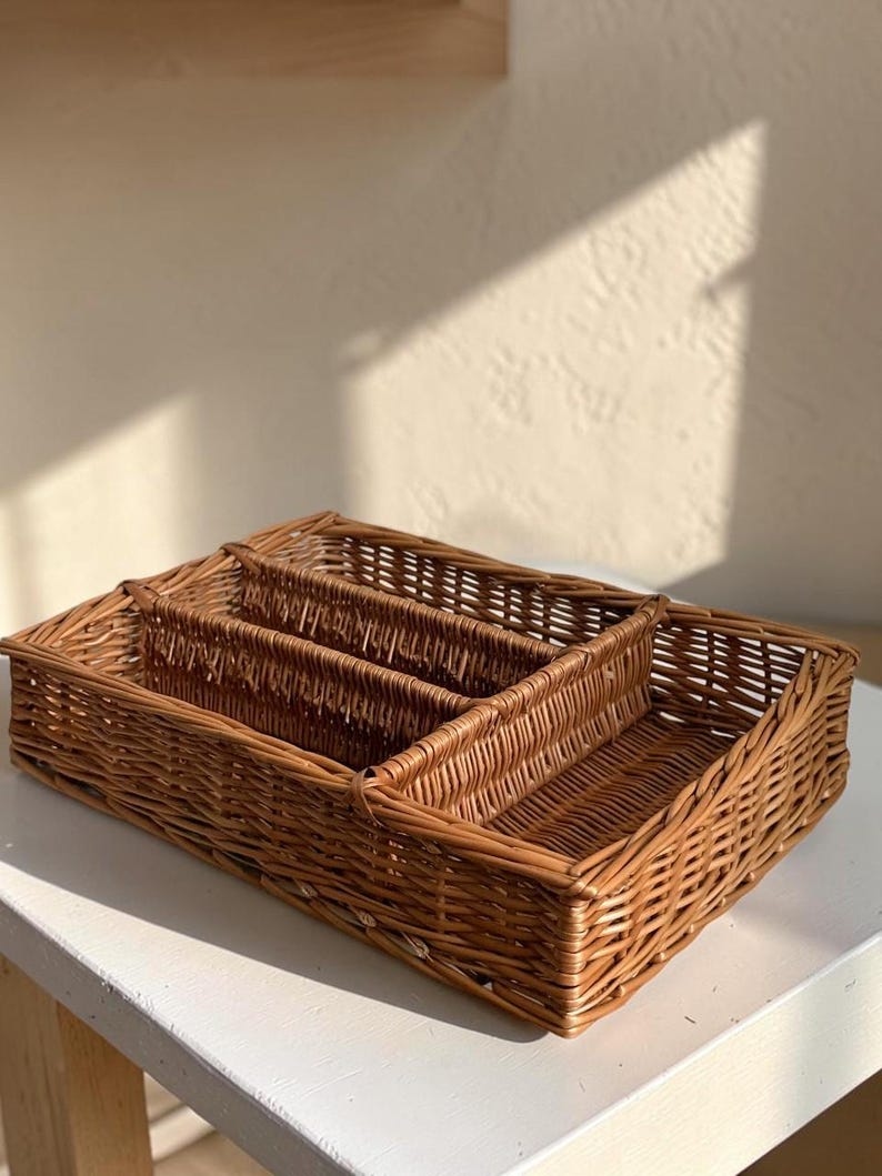 May include: Three woven wicker baskets of varying sizes nested together. The largest basket is rectangular, with the smaller baskets fitting inside. The baskets are a warm brown color and appear to be made of natural materials.