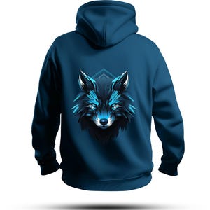 Könnte beinhalten: Ein tealblauer Kapuzenpullover mit einem stilisierten Wolfskopf-Motiv auf dem Rücken. Das Wolfsdesign hat blaue und schwarze Akzente, mit leuchtend blauen Augen und geometrischen Formen. Der Hoodie hat eine Kapuze und lange Ärmel.