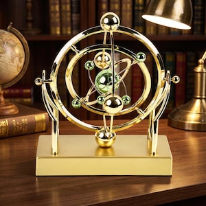 May include: A gold-colored, kinetic sculpture with a planetary design. The sculpture features a central green glass sphere surrounded by orbiting spheres and rings. It sits on a rectangular gold base, creating a decorative and dynamic display.