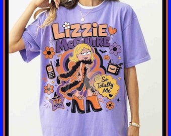 Pode incluir: Uma t-shirt roxo-claro com uma estampa gráfica de uma personagem de desenho animado loira com uma boá de penas preta e sapatos de plataforma. O texto diz Lizzie McGuire e So Totally Me, rodeado por ícones temáticos de Halloween.