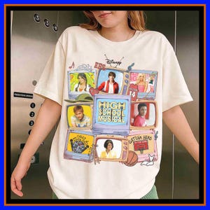 Puede incluir: Una camiseta de color crema con un estampado gráfico de varios televisores de estilo vintage que muestran escenas y personajes de High School Musical. El televisor central muestra el texto High School Musical en letras amarillas.