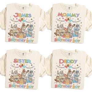 May include: Four cream-colored t-shirts with colorful graphics and text. One shirt says "JAMES" with the number "5", another says "MOMMY", a third says "SISTER", and the last says "DADDY". All shirts have a "BIRTHDAY BOY" graphic.