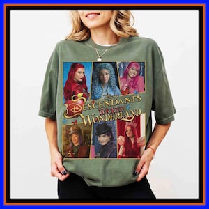 May include: An olive green t-shirt featuring a graphic print of Disney Descendants Wicked Wonderland characters. The design includes five individual character portraits arranged in a grid, with the title text centered in gold lettering.