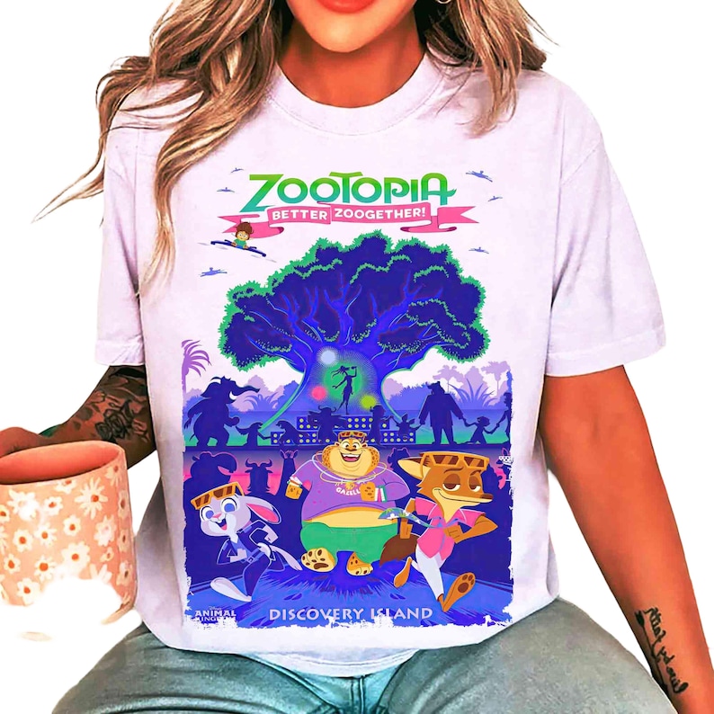 May include: White t-shirt featuring a colorful graphic from the animated film Zootopia. The design includes the film's title, characters, and the phrase "Better Zoogether!" in a whimsical font. The words "Discovery Island" are also visible.