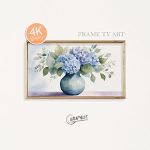 Puede incluir: Pintura de acuarela enmarcada de hortensias azules en un jarrón turquesa. La obra de arte presenta hojas verdes y está sobre un fondo blanco. El marco es dorado y la imagen tiene el texto "4K Quality" y "FRAME TV ART".