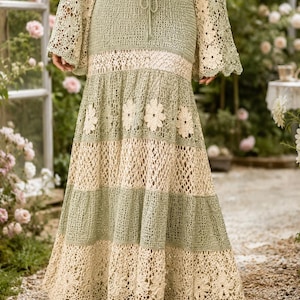 K&ouml;nnte beinhalten: Langer, flie&szlig;ender H&auml;kelrock in Salbeigr&uuml;n und Creme. Der Rock hat ein mehrschichtiges Design mit floralen Akzenten und einem gewellten Saum. Das passende Oberteil hat lange, ausgestellte &Auml;rmel. Perfekt f&uuml;r einen Bohemian- oder Resort-Stil.