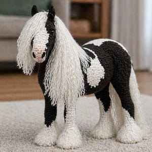 Puede incluir: Figura de caballo de ganchillo hecha a mano en blanco y negro. El caballo presenta una larga melena y cola blancas y fluidas, con marcas blancas en su cuerpo. La figura está sobre una alfombra de color claro.