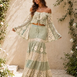 K&ouml;nnte beinhalten: Zweiteiliges H&auml;kel-Outfit in weichem Gr&uuml;n und Creme. Das schulterfreie Oberteil hat lange, ausgestellte &Auml;rmel. Der Rock ist maxilang mit floralen Akzenten. Das Outfit ist aus zarter, offen gewebter H&auml;kelarbeit.