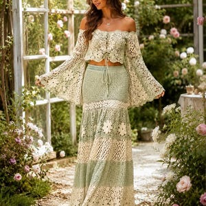 K&ouml;nnte beinhalten: Zweiteiliges H&auml;kel-Outfit in Creme und Hellgr&uuml;n. Das schulterfreie Oberteil hat lange, ausgestellte &Auml;rmel. Der Maxirock hat abwechselnde Streifen in Creme und Gr&uuml;n sowie Blumenmuster. Das Outfit wird im Freien getragen.