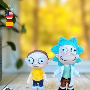 May include: Two crocheted figures of cartoon characters, one with brown hair and a yellow shirt, the other with blue hair and a white lab coat. The figures are handmade and stand on a wooden surface. The image includes a "PDF Pattern" graphic.