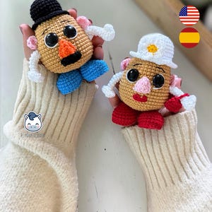 Può includere: Due giocattoli all'uncinetto a forma di patata, uno con cappello nero e scarpe blu, l'altro con cappello bianco e scarpe rosse. Entrambi hanno grandi occhi, nasi arancioni e baffi neri. I giocattoli sono fatti a mano.