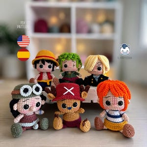 May include: A collection of six crocheted character dolls, each with unique features and outfits. The dolls have large, expressive eyes and are seated. The characters include a doll with a yellow hat, one with green hair, and one with orange hair.