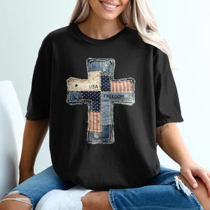 以下が含まれることがあります： パッチワークの十字架のデザインが特徴の黒いTシャツ。十字架は、デニム、星、ストライプ、そして「USA」と「Freedom」の言葉で愛国的な要素を取り入れています。このシャツはカジュアルなスタイルです。