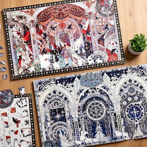 Pode incluir: Dois quebra-cabeças completos com designs intrincados, um com uma cena de catedral de vitrais com elementos vermelhos, brancos e pretos, e o outro com um tema celestial azul e branco. Uma pequena planta em vaso é visível.