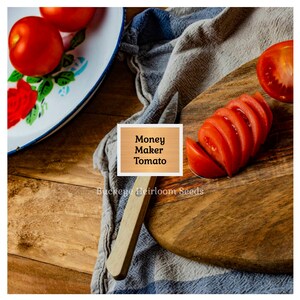 Puede incluir: Imagen de naturaleza muerta con tomates rojos maduros, uno cortado en una tabla de madera. Un plato vintage con dise&ntilde;os florales y un cuchillo tambi&eacute;n est&aacute;n presentes. Se muestra el texto "Money Maker Tomato".