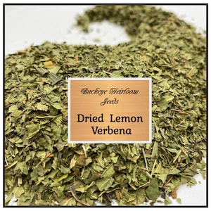 May include: Dried Lemon Verbena from Buckeye Heirloom Seeds. The image shows a pile of dried green leaves, with a light brown label in the center. The label reads "Buckeye Heirloom Seeds" and "Dried Lemon Verbena".