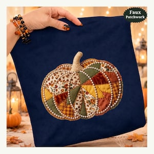 May include: A dark navy blue fabric item featuring a central faux patchwork pumpkin design. The pumpkin is composed of various autumn-toned fabric segments in orange, green, and brown, accented with white pearl-like beads and a textured stem.