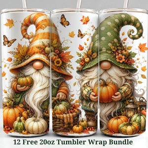 May include: Three cylindrical tumblers featuring a fall-themed design with two gnomes wearing tall hats, one orange striped and one green polka-dotted. The gnomes are surrounded by pumpkins, autumn leaves, butterflies, and a lantern.