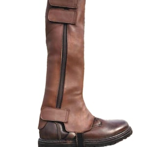May include: A brown leather riding boot with a zipper closure and adjustable straps. The boot features a rounded toe and a sturdy sole. The boot's height is approximately 18 inches.
