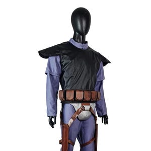 K&ouml;nnte beinhalten: Ein Ganzk&ouml;rperkost&uuml;m auf einer Schaufensterpuppe. Das Kost&uuml;m hat ein schwarzes Brustteil, ein helllila Hemd und Hose sowie einen braunen G&uuml;rtel mit Taschen. Braune Holster sind an den Beinen befestigt. Die Schaufensterpuppe steht auf einer grauen Basis.