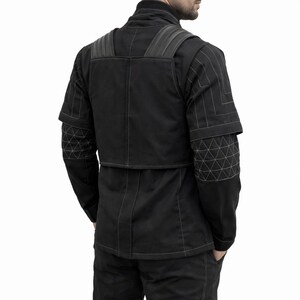 Puede incluir: Chaqueta y pantal&oacute;n negros con costuras blancas. La chaqueta tiene un dise&ntilde;o &uacute;nico con patrones geom&eacute;tricos en las mangas y los hombros. El conjunto parece estar hecho de una tela duradera, posiblemente t&eacute;cnica.