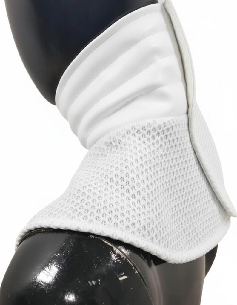 Może przedstawiać: Biały kołnierz szermierczy, zaprojektowany do ochrony szyi. Posiada warstwową konstrukcję z pikowaną g&oacute;rną częścią i oddychającą dolną częścią z siatki. Kołnierz jest przeznaczony do szermierki.