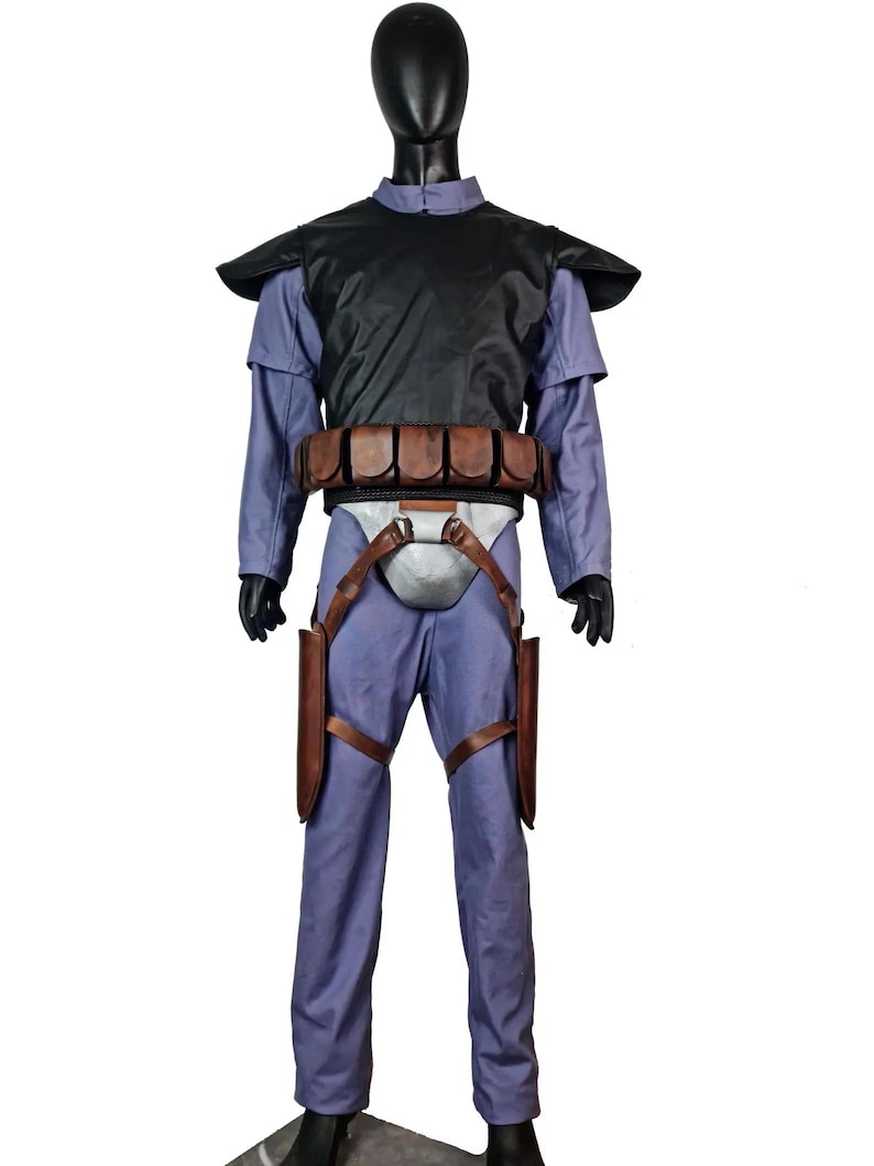 K&ouml;nnte beinhalten: Ein komplettes Kost&uuml;m auf einer Schaufensterpuppe. Es besteht aus einer schwarzen Weste, einem hellblauen Hemd und einer Hose sowie einem braunen G&uuml;rtel mit Taschen. Braune Holster sind an den Beinen befestigt. Das Kost&uuml;m hat ein futuristisches oder Science-Fiction-Design.