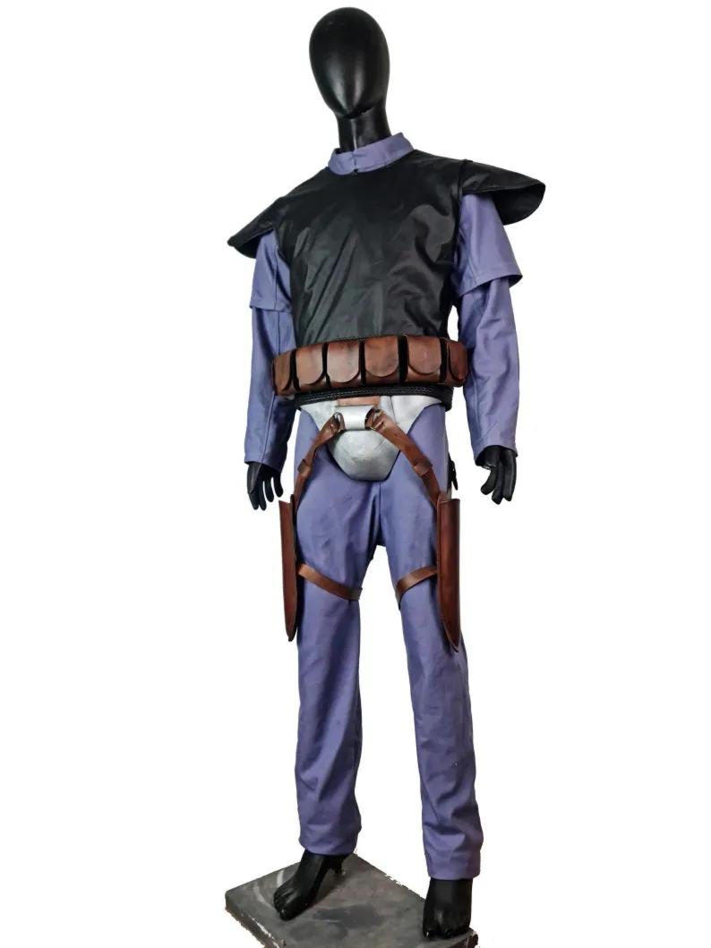 K&ouml;nnte beinhalten: Ein Kost&uuml;m, das auf einer Schaufensterpuppe ausgestellt ist. Das Kost&uuml;m umfasst einen blauen Overall, eine schwarze Weste, einen braunen G&uuml;rtel mit Taschen und braune Halfter. Die Schaufensterpuppe ist schwarz und das Kost&uuml;m wird auf einer grauen Basis pr&auml;sentiert.