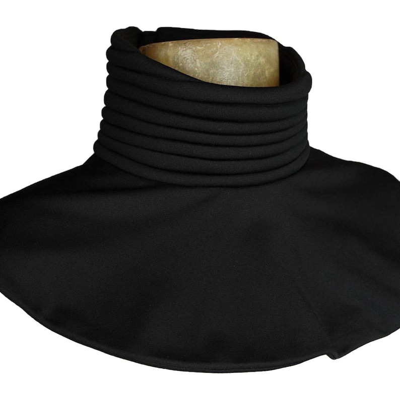 Puede incluir: Un calentador de cuello negro con un cuello alto y acanalado y una base ancha y acampanada. El cuello est&aacute; hecho de m&uacute;ltiples capas apiladas, creando una apariencia texturizada. El calentador de cuello est&aacute; dise&ntilde;ado para brindar calidez y protecci&oacute;n.