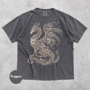 May include: A charcoal gray short-sleeve t-shirt featuring a large, intricate graphic of a dragon composed of floral and vine patterns in a light beige color. The shirt has a crew neckline and a faded, washed-out appearance. The word Pepper is visible.
