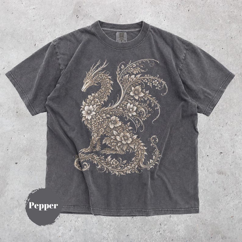 May include: A charcoal gray short-sleeve t-shirt featuring a large, intricate graphic of a dragon composed of floral and vine patterns in a light beige color. The shirt has a crew neckline and a faded, washed-out appearance. The word Pepper is visible.