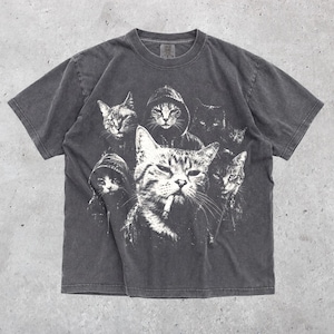 K&ouml;nnte beinhalten: Ein anthrazitfarbenes Kurzarm-T-Shirt mit einem wei&szlig;en Grafikdruck von mehreren Katzen. Die zentrale Katze ist mit einer Zigarette im Mund dargestellt, w&auml;hrend andere Katzen Kapuzenpullover tragen, was ein geschichtetes, monochromes Design ergibt.