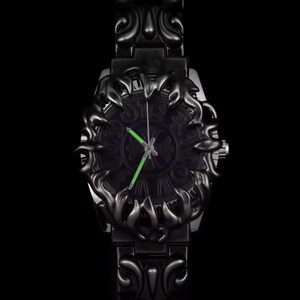 May include: Black wristwatch with an ornate, dark design. The watch face features a detailed pattern and bright green hands. The watch band and bezel have a matching, decorative style. The watch is set against a black background.
