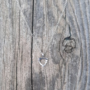 May include: A silver chain necklace with a triangular pendant. The pendant is made of twisted silver wire and has a geometric design.