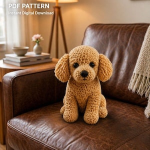 May include: A crocheted tan dog sits on a brown leather sofa. The dog has floppy ears, a black nose, and black eyes. The text "PDF PATTERN Instant Digital Download" is in the upper left corner.