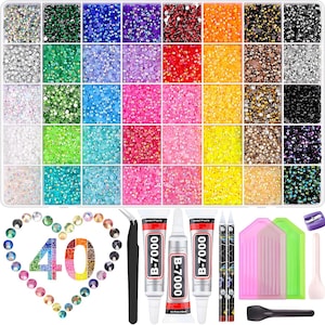 May include: A craft kit with a variety of colorful rhinestones in a divided container. Includes tools like tweezers, glue, and applicators. A heart-shaped arrangement of rhinestones spells out the number 40.