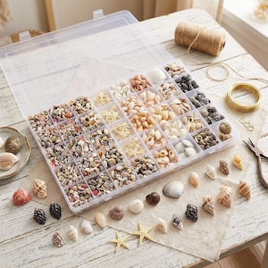 May include: A clear plastic storage container with many compartments filled with various small seashells and starfish. Loose seashells, a spool of twine, a coil of gold wire, and metal pliers are arranged around the container on a white surface.