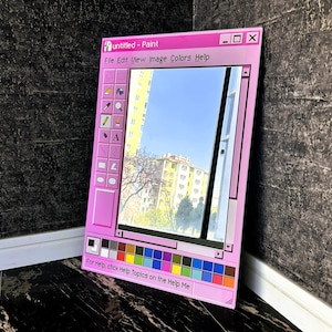 Puede incluir: Un espejo con marco rosa dise&ntilde;ado para parecerse a la cl&aacute;sica aplicaci&oacute;n Windows Paint. El espejo refleja una vista de un edificio y el cielo. El texto "untitled - Paint" est&aacute; en la parte superior, con una barra de herramientas a la izquierda y una paleta de colores en la parte inferior.