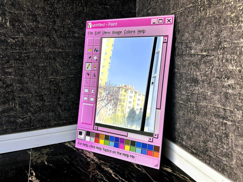Puede incluir: Un espejo con marco rosa dise&ntilde;ado para parecerse a la cl&aacute;sica aplicaci&oacute;n Windows Paint. El espejo refleja una vista de un edificio y el cielo. El texto "untitled - Paint" est&aacute; en la parte superior, con una barra de herramientas a la izquierda y una paleta de colores en la parte inferior.