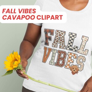 Puede incluir: Una camiseta blanca con el texto FALL VIBES en letras de bloque con varios patrones, incluyendo cuadros, estampado de leopardo y flores. Una pequeña ilustración de un perro Cavapoo marrón con un pañuelo rojo se sitúa bajo el texto.
