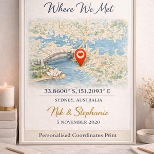 Pode incluir: Impressão emoldurada com um mapa de Sydney, Austrália, com a Sydney Harbour Bridge e a Ópera. O texto "Where We Met" está no topo, com nomes e uma data abaixo. Inclui coordenadas.
